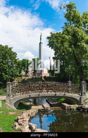 Riga park, view on a summer afternoon of an ornamental bridge in Bastion Hill Park and of the Freedom Monument in the City Canal area of Riga, Latvia. Stock Photo