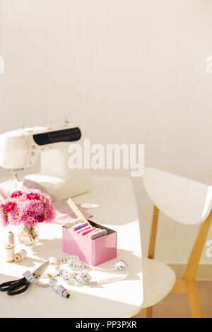 Workplace for sewing and needlework in a bright room with white furniture. Blurring effect and selective focus. Stock Photo