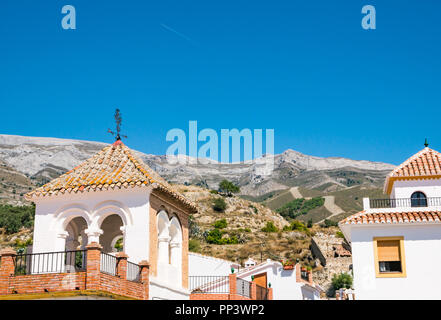 Picturesque tiled rooftops with mountain backdrop in old traditional hilltop village with plane jet trail in sky, Sedella, Axarquia, Andalusia, Spain Stock Photo