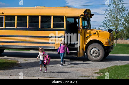 young children getting off yellow school bus Stock Photo