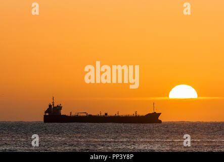 Crosshaven, Cork, Ireland. 25th September, 2017. Oil tanker Thun Galaxy silhouetted by the rising Sun while at anchor outside Cork Harbour, Ireland.- Stock Photo