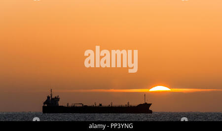 Crosshaven, Cork, Ireland. 25th September, 2017. Oil tanker Thun Galaxy silhouetted by the rising Sun while at anchor outside Cork Harbour, Ireland.- Stock Photo