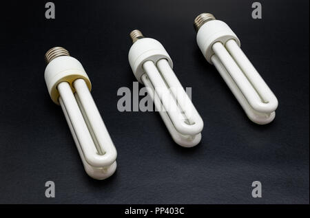 Three energy-saving bulbs lying on a black table. Stock Photo