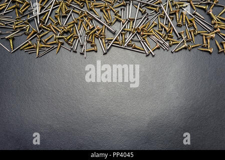 Screws and nails for wood, lying on a black background. Stock Photo