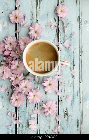 Coffee and pink cherry blossoms on a rustic wooden background Stock Photo