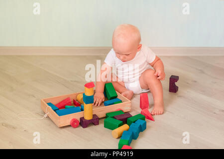 Cute little baby playing with colored wooden blocks in the room. Early development concept Stock Photo