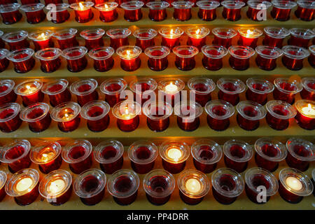 Many lighted candles in candlesticks. Sacred light. Burning candles in church. Concept of religion. Bright yellow light in the evening, close-up Stock Photo