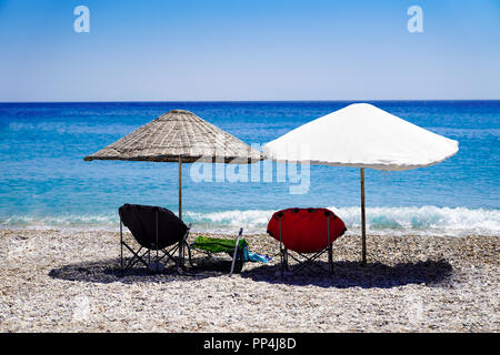 Parasols and deck chairs on the beach by the sea Stock Photo