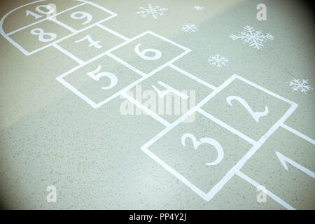 Hopscotch court with numbers from 1 to 10 drawn with white paint on the asphalt.Child playing hopscotch game.activities for children.School yard.Copy space Stock Photo