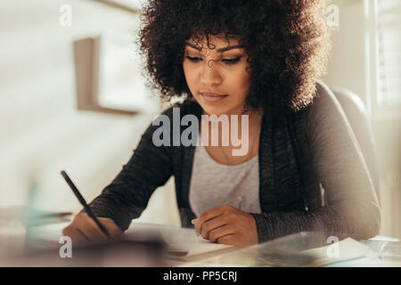 Portrait of female architect working at her desk. Busy female designer working on new building plan while sitting at office table. Stock Photo