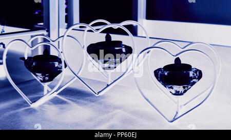 Three flaming candles on hearts metal candle stand. Holidays decoration. Stock Photo