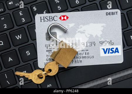 Unlocked padlock and debit card on a computer keyboard.  Online financial security concept.  NB: Data anonymised. Stock Photo