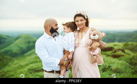 Hispanic family of three standing on green hill background Stock Photo