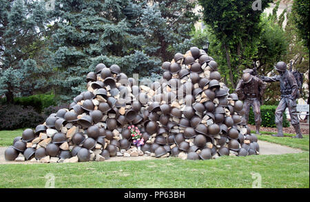 Pile of war dead helmets memorial in Zanesville, Ohio—somber tribute to fallen soldiers through symbolic military sculpture. Stock Photo