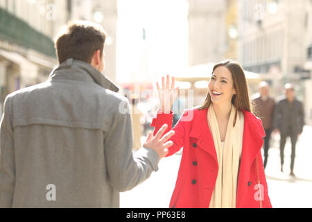 Two happy friends meeting and greeting in the street of a big city Stock Photo