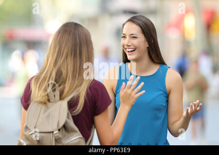 Two happy friends meeting and greeting on the street with a blurred background Stock Photo