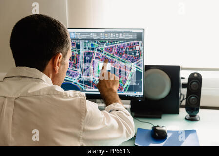 Architect drawing with cad software designing building. Rear view. He is pointing the screen Stock Photo