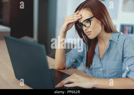 Young disappointed feelancer woman reading bad news on laptop indoors Stock Photo