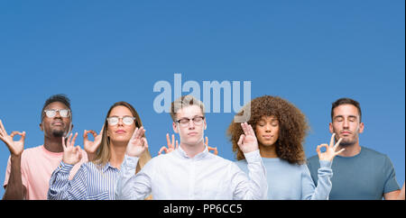 Composition of group of friends over blue blackground relax and smiling with eyes closed doing meditation gesture with fingers. Yoga concept. Stock Photo
