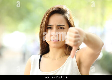 Front view portrait of an angry teen refusing with thumb down in the street Stock Photo