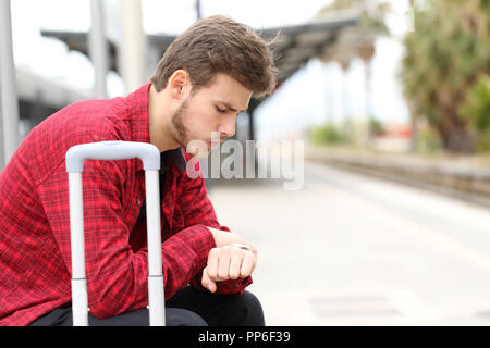 Worried traveler looking at his watch waiting for delayed train Stock Photo