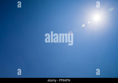 Lens flare optical effect over blue sky with shining sun Stock Photo