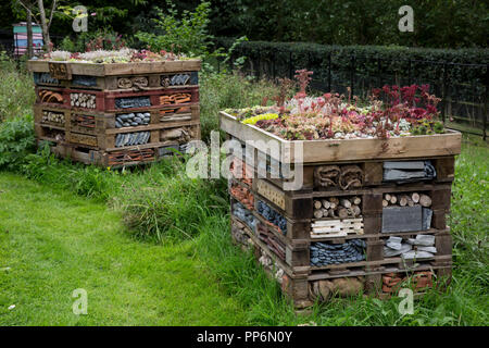 Two large bug houses with several layers of different materials in a garden. Stock Photo