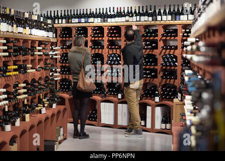Wine racks in a wine shop: “Aux cinq sens”, in Tain-l'Hermitage (south-eastern France), selling wines and spirits. Wine merchant advising a customer,  Stock Photo