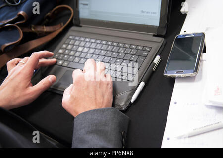Note-taking on a computer during a business meeting: someone’s hands typing on a keyboard Stock Photo