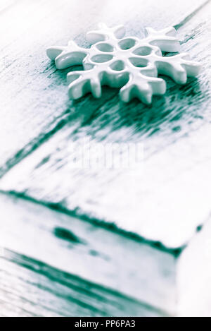 White winter season greetings card background. Porcelain Christmas decoration snowflake on grunge wooden textured table. Black and white photo Stock Photo