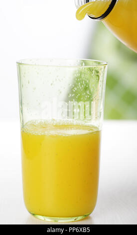 Pouring orange juice from the bottle to the glass Stock Photo