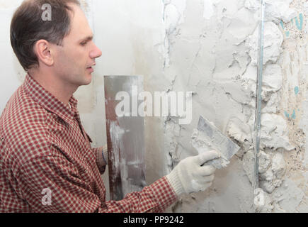 Worker plastering a wall using trowel Stock Photo