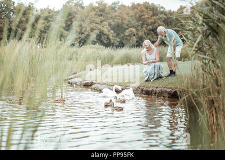 Positive delighted senior people spending time near lake Stock Photo