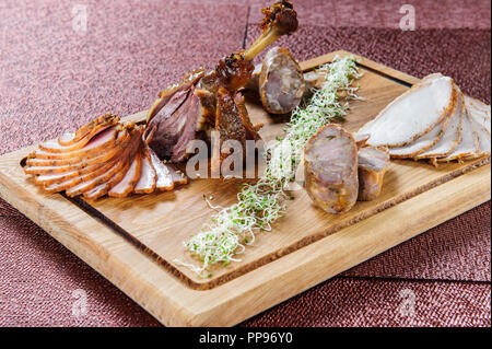 Baked goose leg in berry sauce on a ceramic plate on a white wooden background. Stock Photo