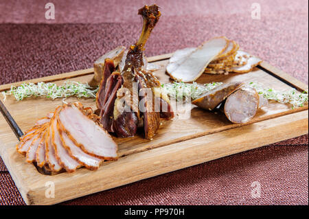 Baked goose leg in berry sauce on a ceramic plate on a white wooden background. Stock Photo