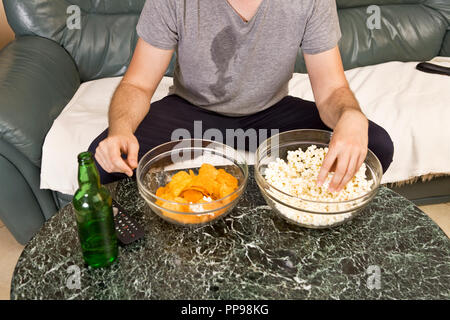 A young man watches television and changes channels while relaxing Stock Photo