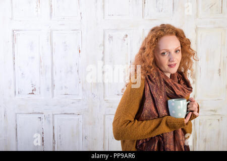 Beautiful red-haired woman holding mug of coffee Stock Photo