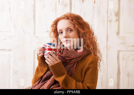 Woman holding union jack cup, looking concerned Stock Photo