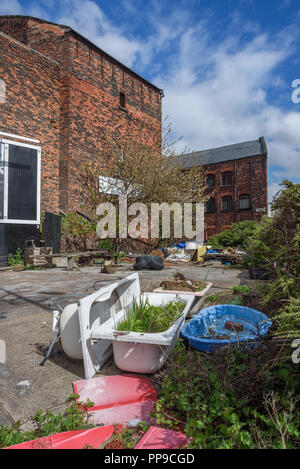 Discarded junk around old brick warehouses in LIverpool docklands. Stock Photo