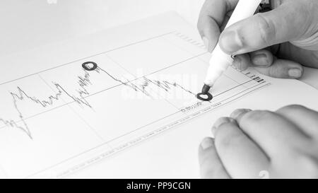 Black and white image of financial analyst drawing financial graph with marker Stock Photo