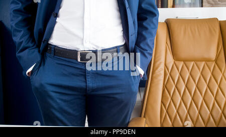 Closeup image of businessman in blue suit standing at office and holding hands in pockets Stock Photo