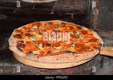 Fresh original Italian pizza is prepared and baked in a traditional italian wood fire stone brick oven i a restaurant in Baguio City, Philippines Stock Photo