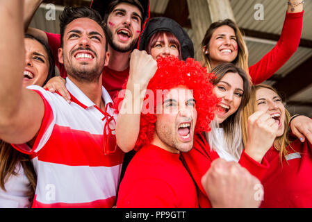 Football supporters at the stadium - Football fans having fun and looking at football match Stock Photo