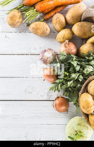 Close-up assortment of fresh vegetables. Potatoes onion carrot celery kohlrabi and garlic on wood. Stock Photo