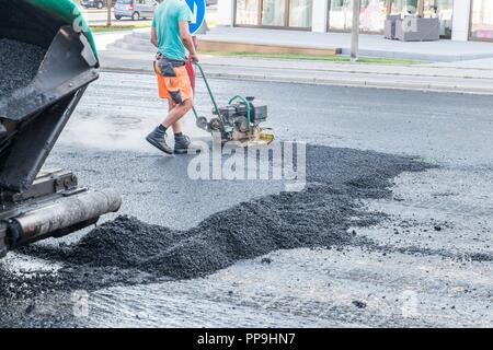 Road workers compact the asphalt with a vibrating rammer on the road, Germany Stock Photo