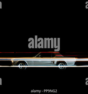 A view of a vintage classic American muscle sports car and light trails by traffic in Venice beach, California at night time Stock Photo