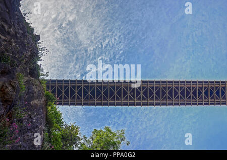 Bristol, England, June 1, 2014: View from the bank of the river Avon up to the bridgedeck of the Clifton suspension bridge against a blue sky with fle Stock Photo