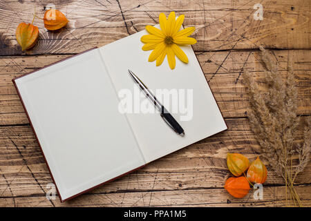 Autumn flowers and Notepad for text on wooden background with copy space Stock Photo