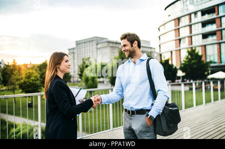 Young businessman and businesswoman shaking hands outdoors. Stock Photo