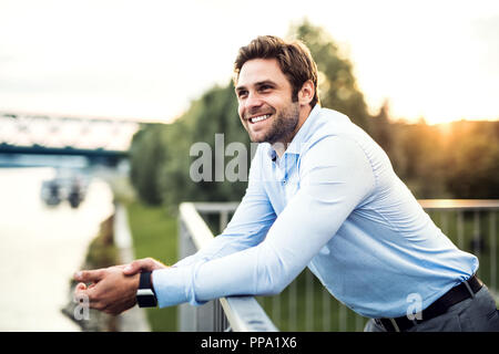 A young businessman standing on a bridge, leaning on a railing. Stock Photo